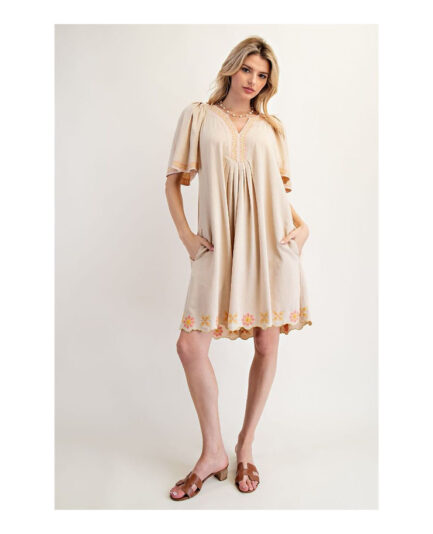 woman posing with hands on hip wearing cream dress.